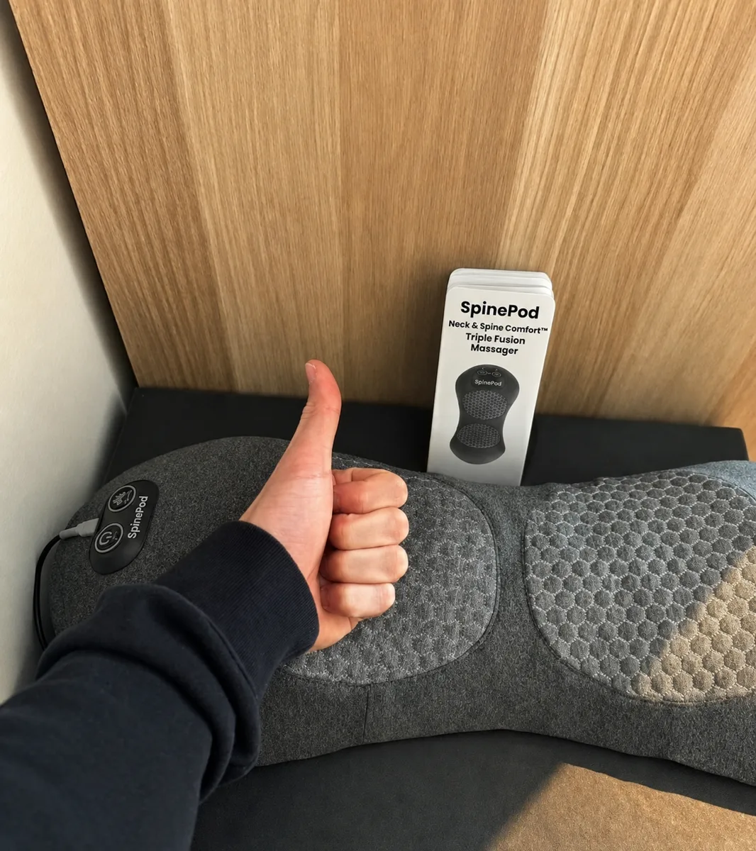 Cliente satisfaite montrant son pouce levé à côté de son SpinePod et de sa boîte